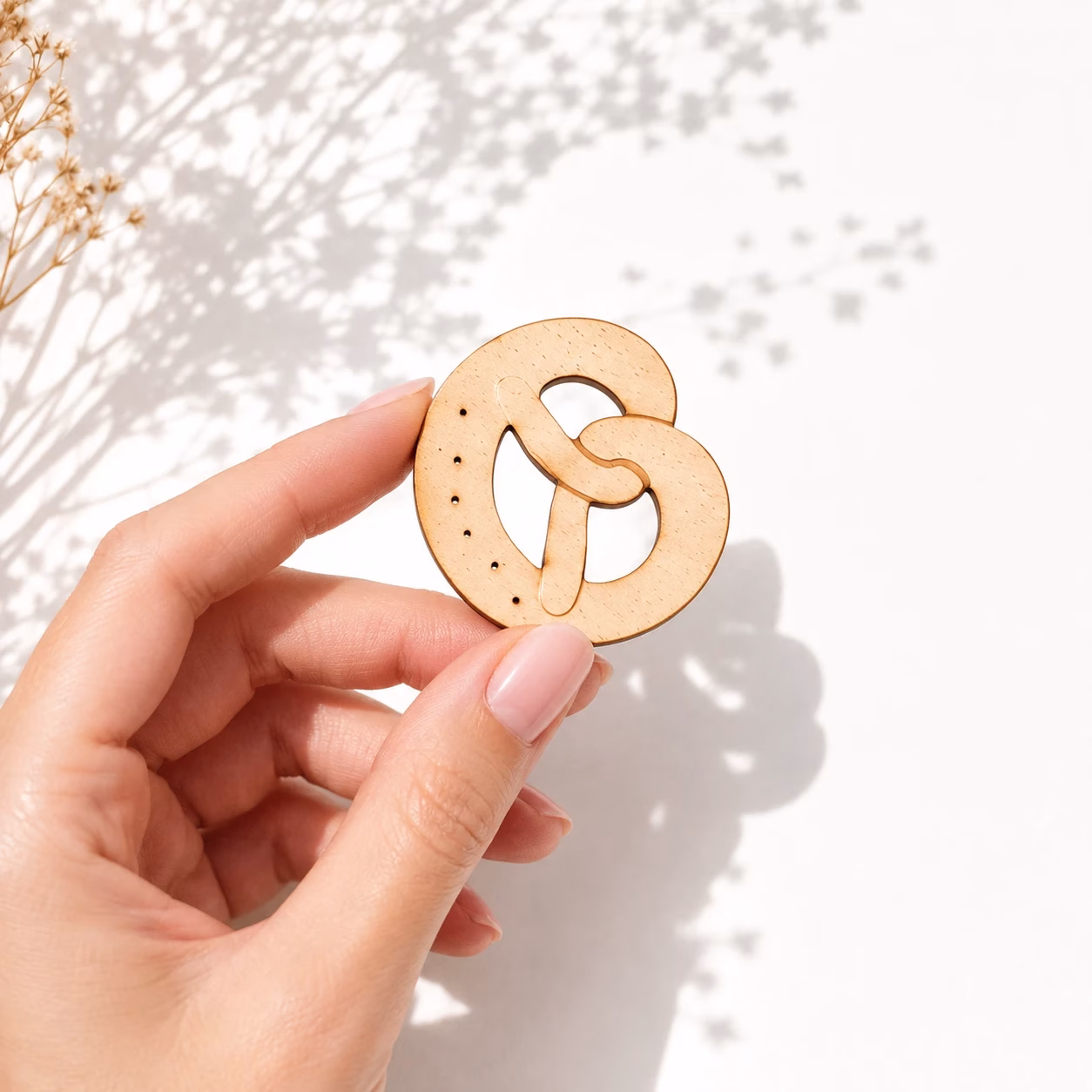 Miniatur Holzbrezel in der Hand als Größenvergleich für Tischdeko
